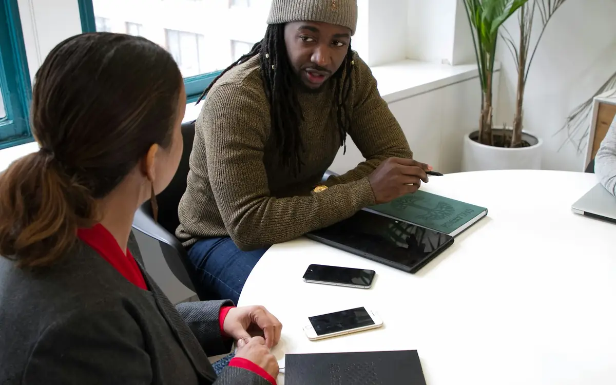 Two colleagues working through a plan with notebooks and phones