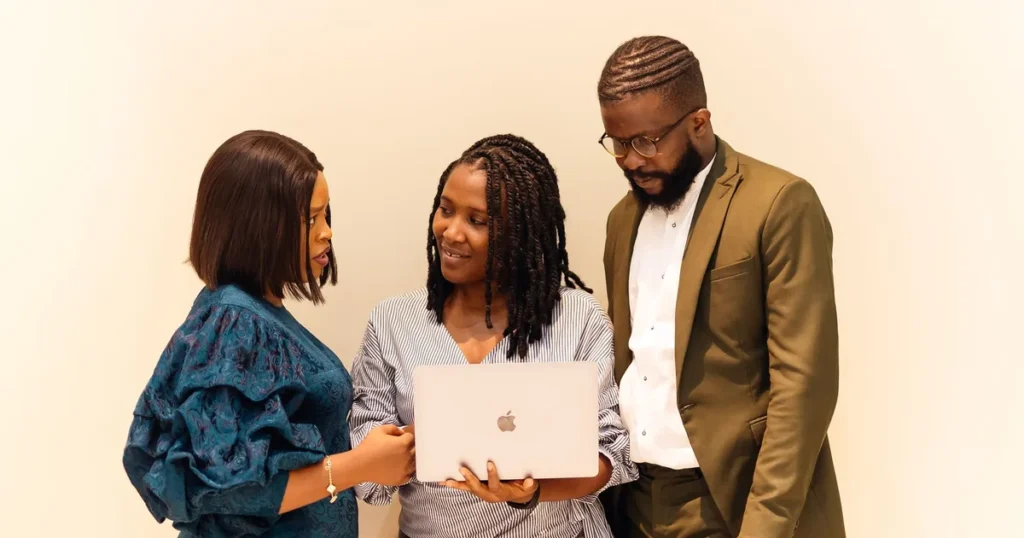 Three business professionals reviewing a digital marketing proposal on a laptop