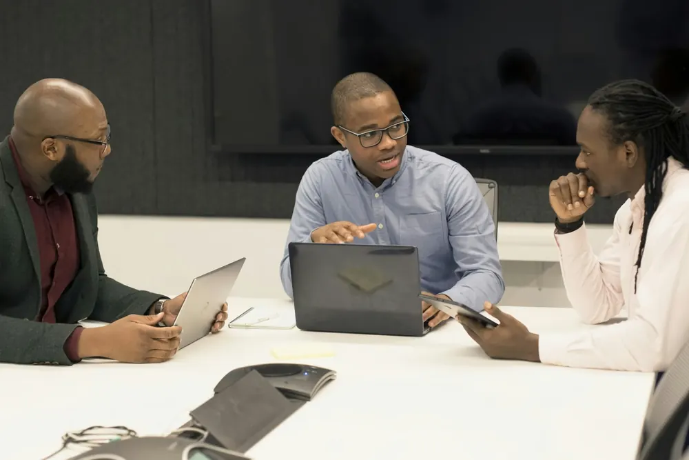 Three colleagues discussing a marketing plan around a laptop