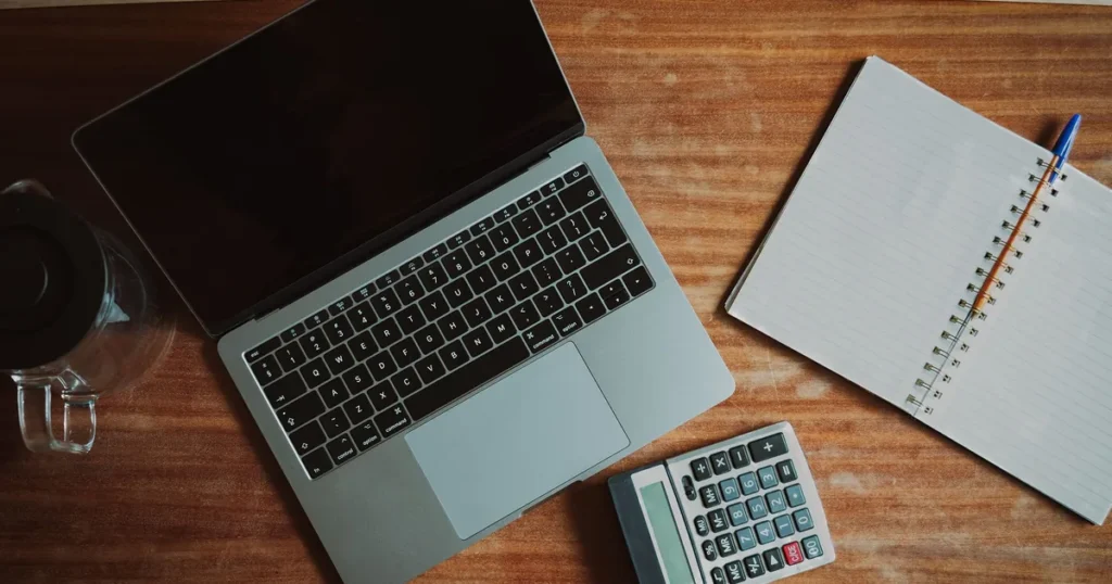 Laptop, calculator and notebook on a wooden desk, planning a website budget in Kenya